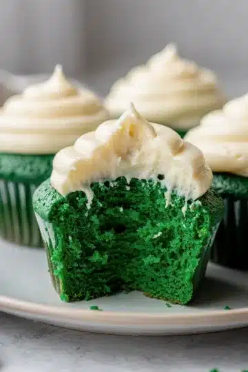 Green Velvet Cupcakes 14 Green velvet cupcakes with cream cheese frosting on a rustic wood background.