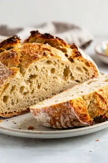 Irish Soda Bread 9 Freshly baked Irish Soda Bread with raisins on a rustic wooden cutting board.