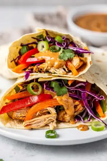 Thai Peanut Chicken Wraps 11 Thai peanut chicken wraps with fresh vegetables and creamy sauce on wood table