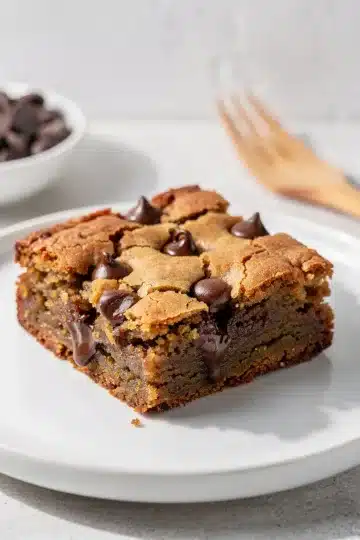 Brown Butter Blondies 12 Golden brown butter blondies with melted chocolate chips on a marble countertop.