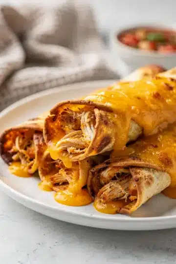 Cheesy Baked Chicken Taquitos 11 Crispy baked chicken taquitos with melted cheese and fresh salsa on wood.