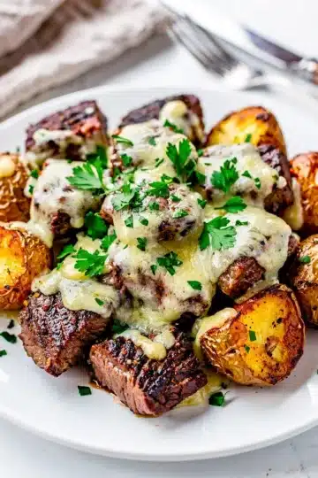 Cheesy Garlic Butter Steak Bites and Potatoes 8 Cheesy garlic butter steak bites and crispy potatoes on a white pan.