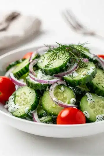 Creamy Creamy Cucumber Dill Salad 13 Creamy cucumber dill salad with fresh tomatoes in a bright white bowl.