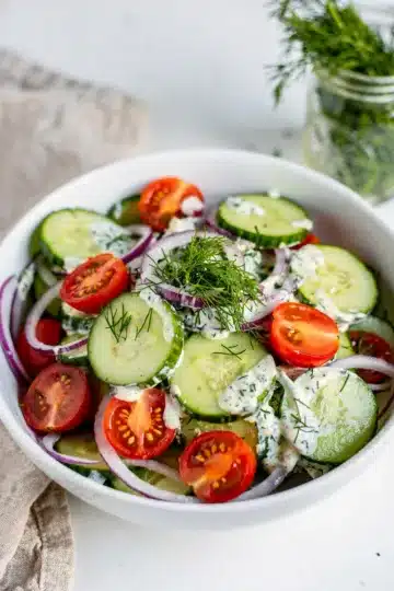 Crisp Creamy Cucumber Dill Salad 14 Creamy cucumber dill salad with fresh tomatoes in a bright white bowl