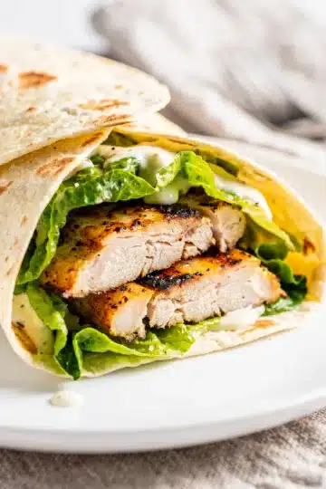 Grilled Chicken Caesar Wrap 11 Grilled chicken Caesar wrap sliced open on a rustic wooden board.