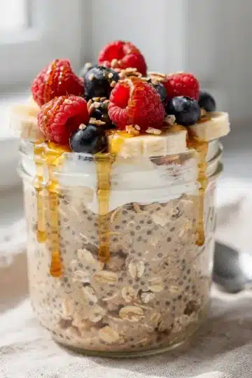 Classic High Protein Overnight Oats 11 Creamy high protein overnight oats with fresh berries and honey in a jar.