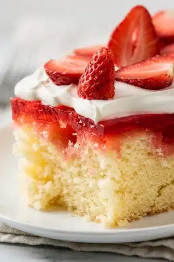 Classic Strawberry Jello Poke Cake 12 Classic strawberry jello poke cake slice with vibrant red gelatin filling and whipped topping