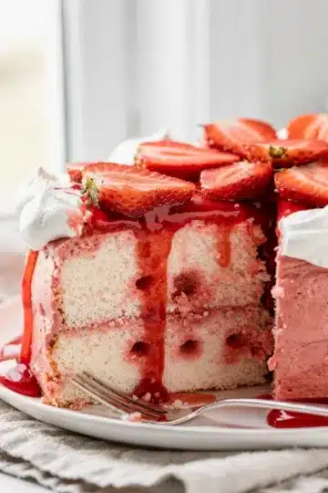 No Bake Strawberry Jello Poke Cake 11 No bake strawberry jello poke cake slice with whipped topping and fresh strawberries.