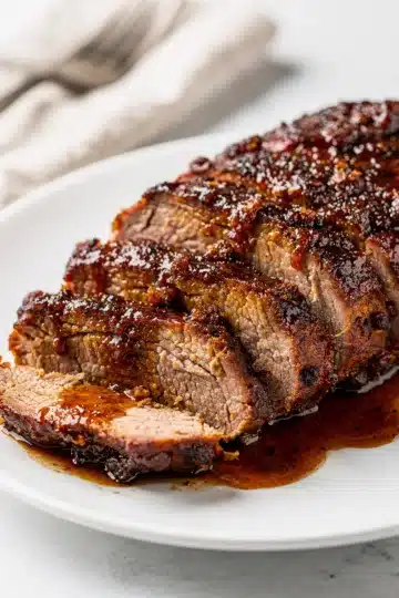Brown Sugar BBQ Pork Tenderloin 14 Juicy pork tenderloin with sticky brown sugar barbecue glaze on white plate