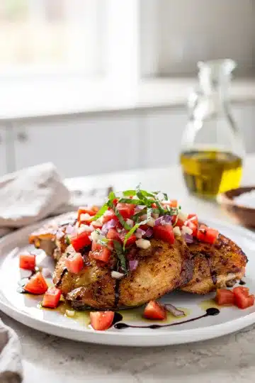 Bruschetta Topped Chicken Thighs 11 Crispy chicken thighs topped with fresh tomato bruschetta on a rustic board.