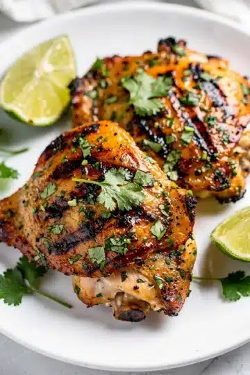Cilantro Lime Grilled Chicken Thighs 13 Cilantro lime grilled chicken thighs with charred marks and fresh lime wedges.