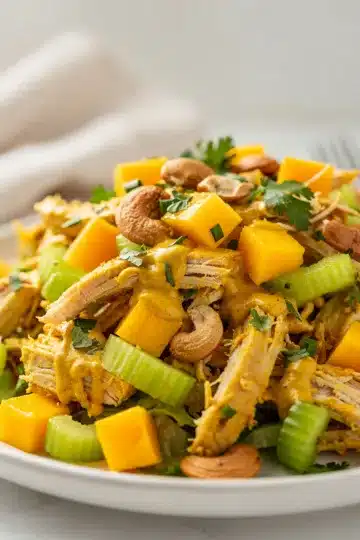 Curried Chicken Salad with Mango 11 Curried chicken salad with mango in a white bowl, featuring vibrant yellow dressing.