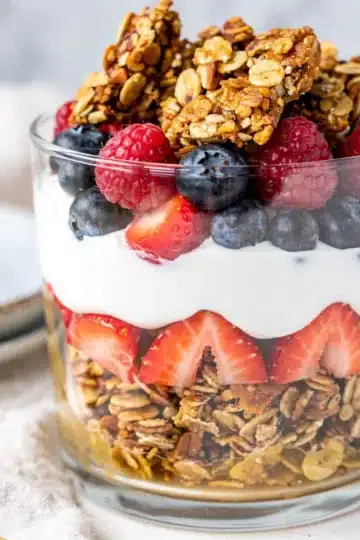 Greek Yogurt Granola Parfait 14 Greek yogurt granola parfait with fresh berries in a clear glass jar.