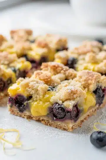 Lemon Blueberry Crumb Bars 14 Golden lemon blueberry crumb bars on white plate, homemade.