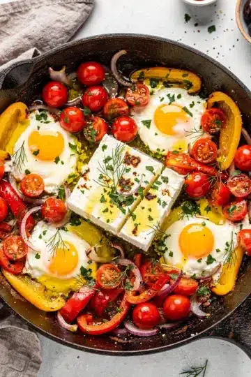 Mediterranean Baked Feta Eggs 11 Mediterranean baked feta eggs with tomatoes and peppers in cast iron skillet