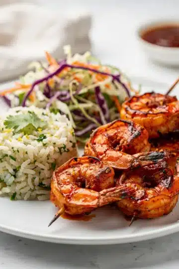 Spicy BBQ Shrimp Skewers 14 Spicy BBQ shrimp skewers with glossy sauce on a wooden board