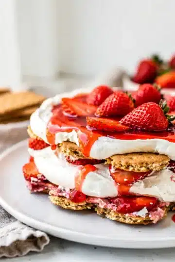Strawberry Shortcake Icebox Cake 13 Layered strawberry shortcake icebox cake slice with whipped cream and berries