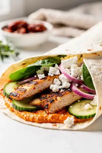 Sun-Dried Tomato Grilled Chicken Wrap 26 Grilled chicken wrap with sun dried tomato spread on rustic wooden board