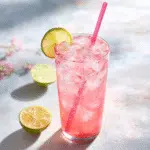 pink salt lime drink on ice with straw and citrus garnish