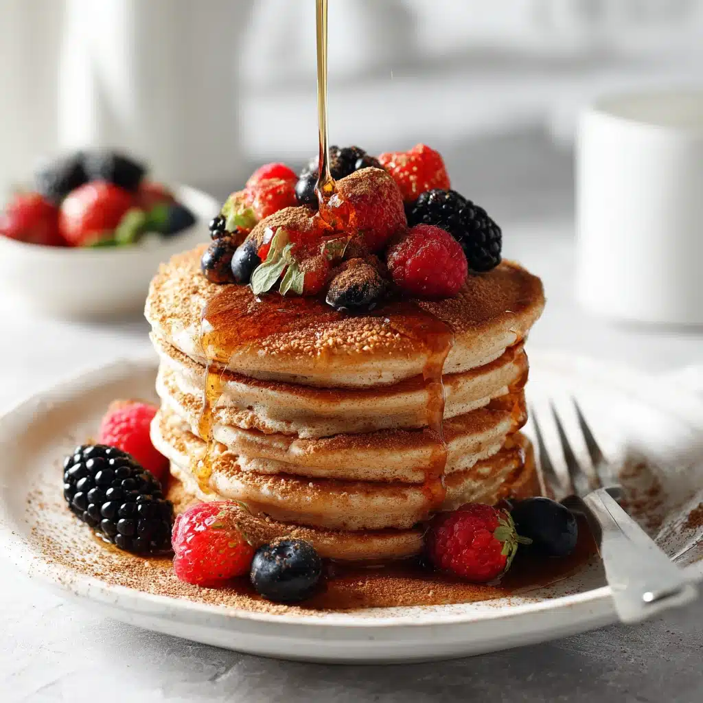 Stack of protein cottage cheese pancakes topped with fresh berries and maple syrup