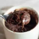 Gooey spoonful of chocolate protein mug cake being lifted from a white mug