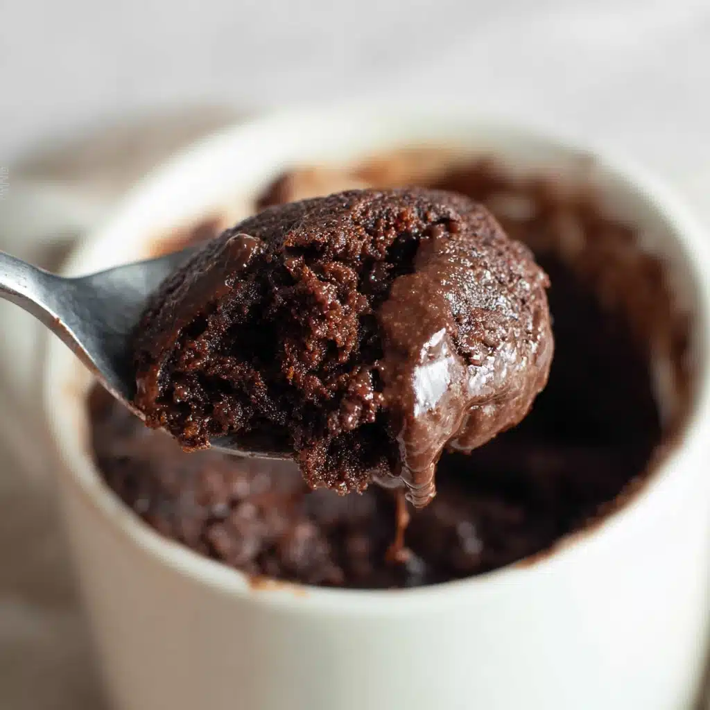 Gooey spoonful of chocolate protein mug cake being lifted from a white mug