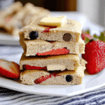 Kodiak Cakes Pancake Recipe squares with strawberries, blueberries, and butter on a white plate