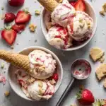 No-churn strawberry shortcake ice cream with fresh strawberries and shortcake chunks in a bowl, styled with cone and toppings for National Ice Cream Day