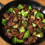 Tender beef slices and vibrant green broccoli in a glossy soy-based sauce, served hot and steaming.