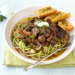 Creamy mushroom stroganoff with sliced mushrooms and herbs, served over whole-grain or zucchini noodles.
