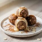 Cinnamon roll protein balls with a sweet yogurt drizzle on a rustic board.