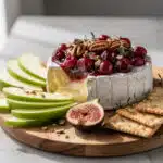 Warm baked brie cheese topped with cranberry sauce and toasted pecans appetizer.