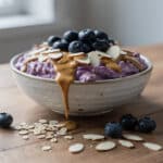 Creamy blended tofu and blueberry oats in a rustic ceramic breakfast bowl.