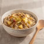 Creamy apple cinnamon oatmeal in a rustic bowl with walnuts and maple syrup