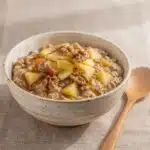 Creamy apple cinnamon oatmeal in a rustic bowl with walnuts and maple syrup
