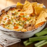 Creamy golden brown buffalo chicken dip in a ceramic dish.