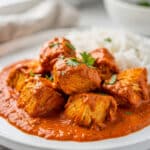 Creamy crockpot chicken tikka masala with naan bread and fresh cilantro garnish.