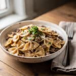 Creamy parmesan garlic beef bowtie pasta in a rustic white bowl.
