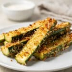 Crispy Parmesan zucchini fries in a bowl with marinara sauce for dipping.