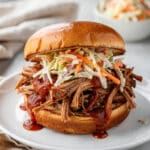 Crockpot BBQ pulled pork sandwich with coleslaw on a brioche bun.