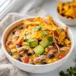 Crockpot chicken tortilla soup with shredded chicken beans corn and avocado garnish