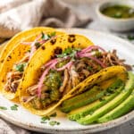 Shredded salsa verde pork in a warm tortilla with fresh toppings.