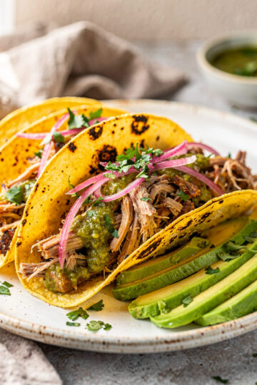 Shredded salsa verde pork in a warm tortilla with fresh toppings.