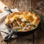 Golden turkey pot pie with flaky crust and creamy vegetable filling on rustic table