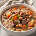 Hearty ham and bean soup recipe in a rustic bowl with fresh bread.