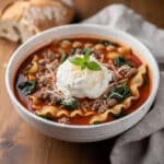 High protein lasagna soup in a rustic bowl with ricotta and basil