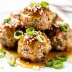Honey garlic meatballs in a glossy sticky sauce on a white plate.