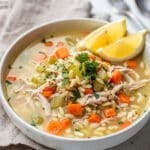 Lemon chicken orzo soup in a bowl with carrots, celery, and fresh parsley.