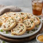 Loaded Everything Bagel Pinwheels appetizer arranged on a rustic wooden serving board.