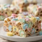 Colorful Lucky Charms marshmallow cereal treats on a rustic white plate.